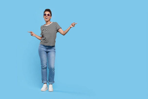Happy young woman in sunglasses dancing on light blue background. Space for text - Fotó, kép