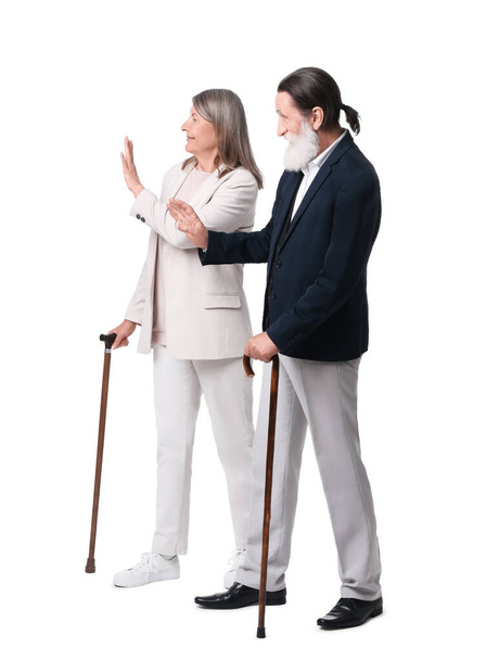 Senior man and woman with walking canes greeting someone on white background - Foto, imagen