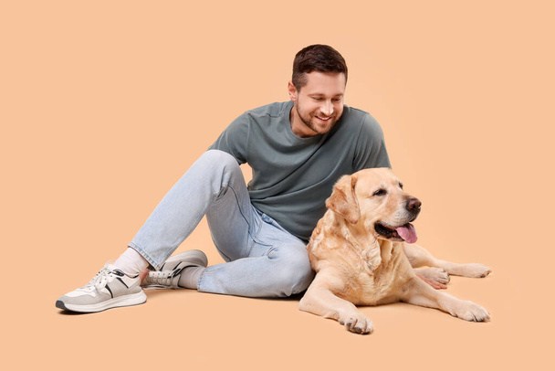Man with adorable Labrador Retriever dog on beige background. Lovely pet - Fotó, kép