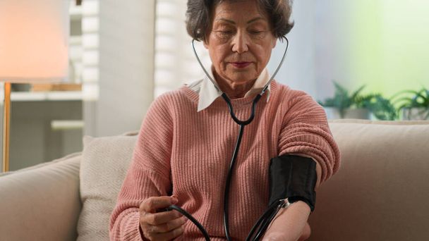 Caucasian grandmother checking low high cardio heart beat senior woman at home old female granny elderly retired lady using portable medical device use digital measuring check blood pressure health - Fotoğraf, Görsel