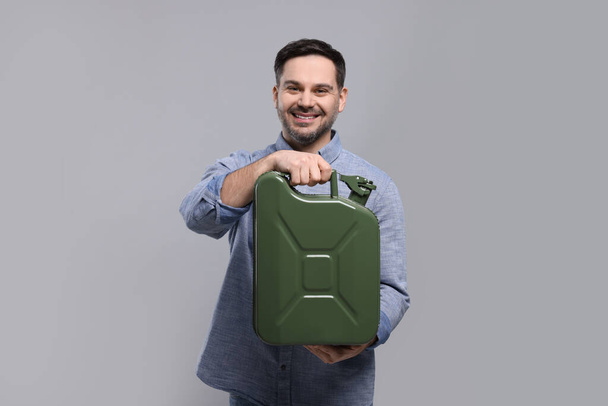 Man holding khaki metal canister on light grey background - Foto, afbeelding