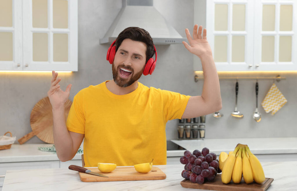 Emotional man listening music with headphones in kitchen - Foto, Bild