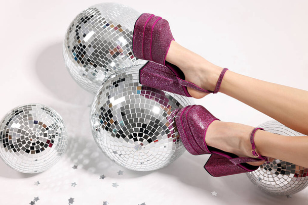 Woman in pink high heeled shoes and disco balls on white background, closeup - Фото, изображение