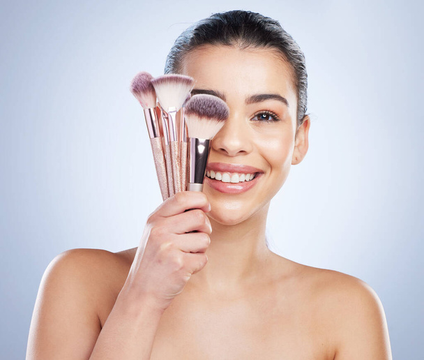 Makeup brush, portrait and happy asian woman studio with cosmetics, tools or application on grey background. Face, smile and lady wellness model with beauty, glamour or contour cover results routine. - Photo, image