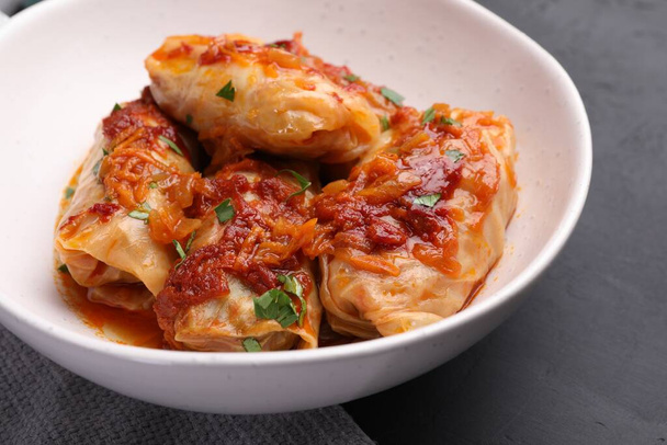 Delicious stuffed cabbage rolls cooked with homemade tomato sauce on black table, closeup - Photo, image