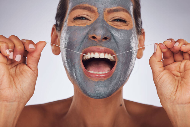 Portrait, face mask and a woman flossing teeth for skincare, dental hygiene and wellness. Happy, cleaning and a model or girl with gear for tooth cleaning and a facial isolated on a studio background. - Фото, изображение