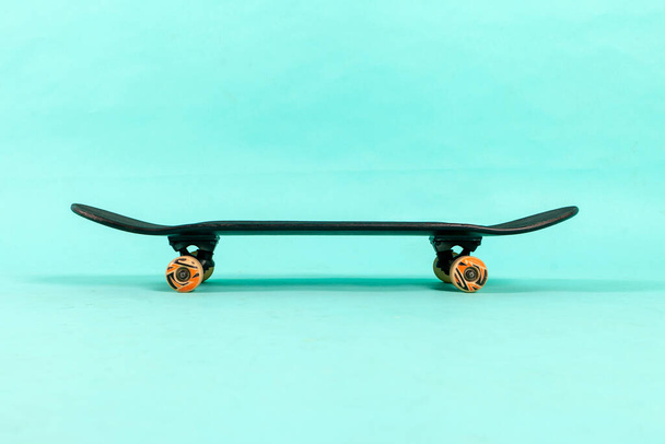 empty black skateboard stands on blue isolated background, equipment for extreme sports of youth, copy space - 写真・画像