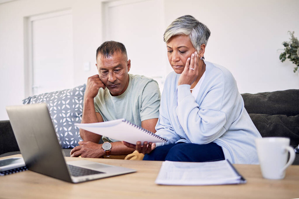 Senior couple, tax documents and stress with laptop in living room for planning, thinking and budget. Elderly man, woman and paperwork for financial compliance, anxiety or debt in retirement on sofa. - Foto, Bild