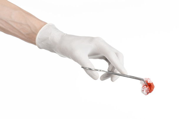 Chirurgie und medizinisches Thema: die Hand des Arztes in einem weißen Handschuh, der einen Chirurgenclip mit einem blutigen Tampon auf weißem Hintergrund im Studio hält - Foto, Bild
