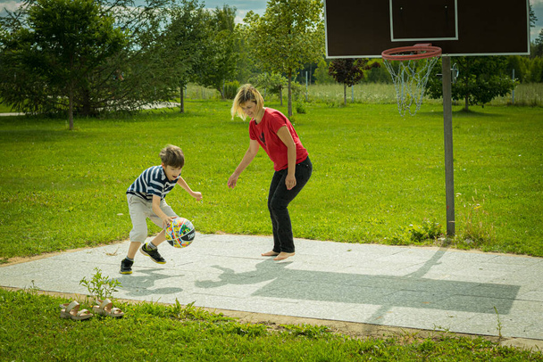 Äiti pelaa koripalloa lapsensa kanssa. Lapsi pelaa koripalloa naisen kanssa - Valokuva, kuva