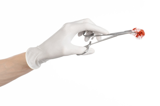 Chirurgie en medische thema: doctor's hand in een witte handschoen houden een chirurgische clip met een bloedige tampon geïsoleerd op een witte achtergrond in studio - Foto, afbeelding