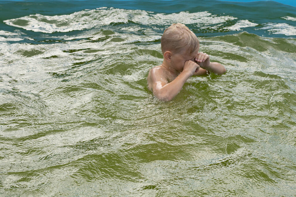 Lapsi hukkuu yksin altaaseen. Lapsi vesilammikon luona. Lasten turvallisuus vesistöjen läheisyydessä - Valokuva, kuva