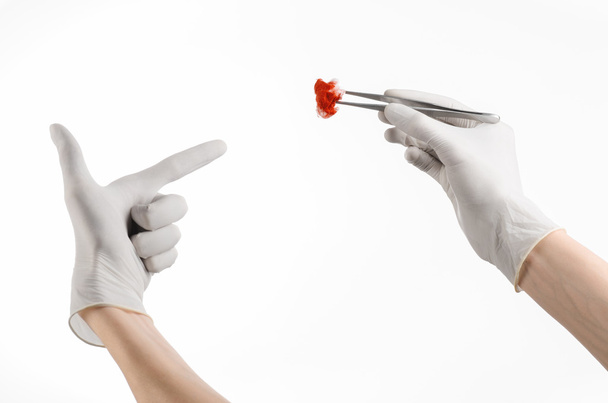 Хирургия и медицинская тема: рука врача в белой перчатке с хирургическим клипом с окровавленным тампоном, изолированным на белом фоне в студии
 - Фото, изображение