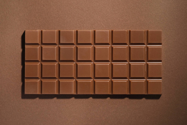 Tasty chocolate bar on brown background, top view - Foto, Bild