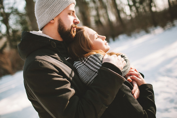 Young hipster couple hugging in winter forest - Fotoğraf, Görsel