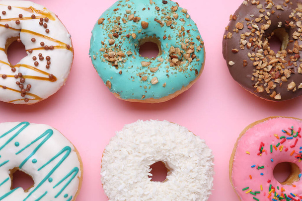 Different tasty donuts on pink background, flat lay - Fotó, kép