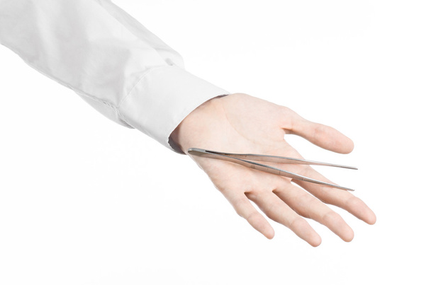 Хирургическая и медицинская тема: рука врача с пинцетом на белом фоне в студии
 - Фото, изображение