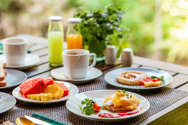 Morning breakfast table at tropical resort. Delicious and healthy meal with fresh fruit, organic eggs, and a glass of orange juice. Concept of summer vacation and a gourmet dining experience. - Valokuva, kuva