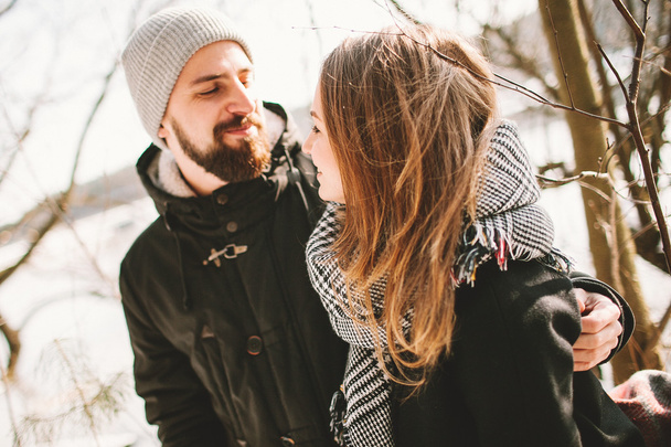 Hipster couple sitting on tree over frozen lake - Foto, imagen