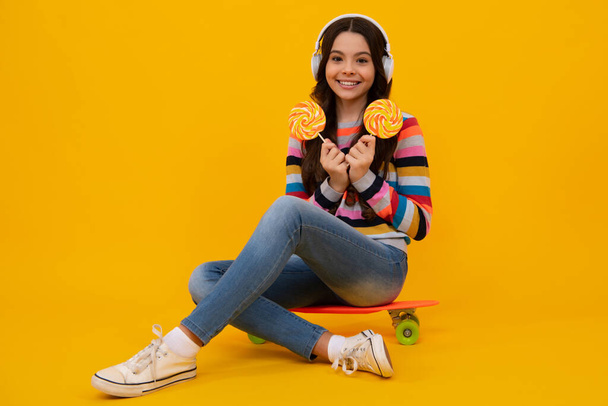 Teenage girl with candy lollipop, happy child 12, 13, 14 years old eating big sugar lollipop, sweets candy. Happy casual teenager, positive and smiling emotions of teen girl - Fotó, kép
