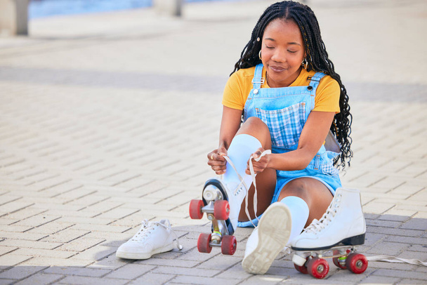 Roller skating, tie and safety with a black woman by the sea, on the promenade for training or recreation. Beach, sports and a young female teenager tying skates on the coast by the ocean or water. - Fotografie, Obrázek