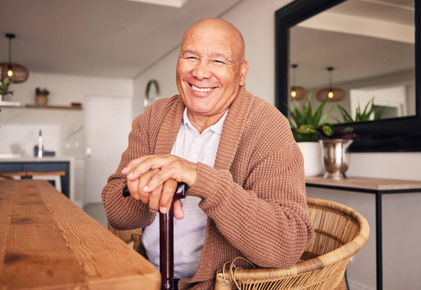 Muotokuva, kävelykeppi ja vanhempi vammainen mies istumassa kotinsa olohuoneessa eläkkeelle siirtymisen aikana. Hymyile, keppi ja rentoudu vanhuksen kanssa ruokapöydän ääressä talossaan.. - Valokuva, kuva