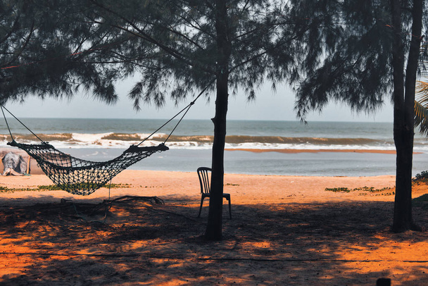 a hammock in shade under trees on a beach by the ocean - Foto, Imagen