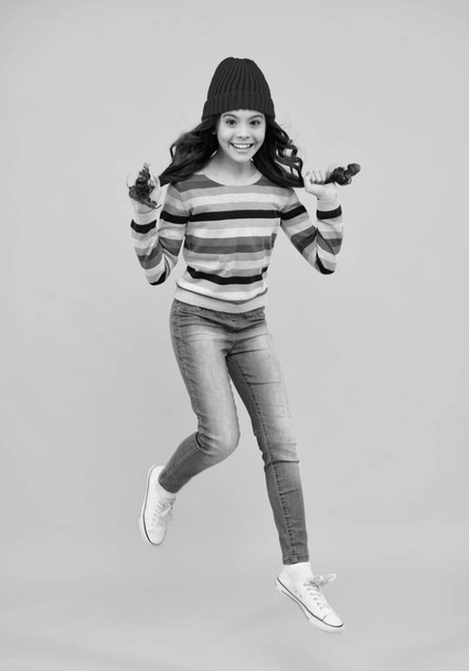 カラフルな青の背景に楽しさを持ってニット帽とセーターでファッション幸せな若い女性。ジャンプして走る。幸せなティーン,正と笑顔感情のティーン女の子 - 写真・画像