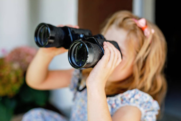 Little Girl Looking through Binoculars. Preschool Child Having Fun with Watching Birds and Plants. Leisure Activity for Children, Small Kids in Summer - Photo, image