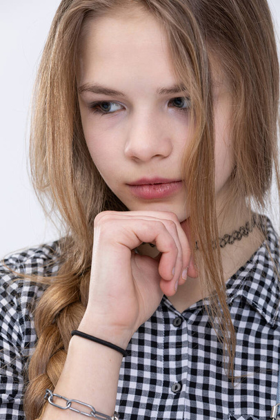 Bust of a thoughtful girl. Close-up of a womans face. Girl with a thoughtful face. Posing on a white background. Photo session in a studio. Person wearing checkered shirt. - Foto, imagen