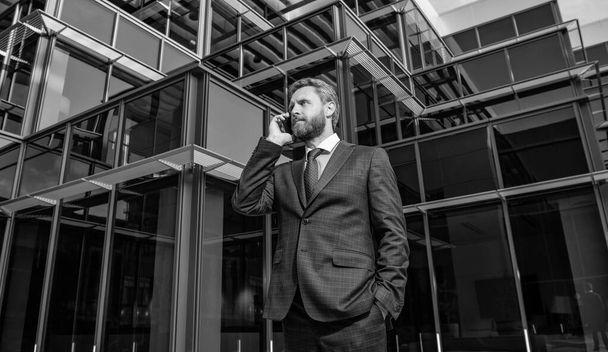 charismatický podnikatel v obleku má telefonní hovor mimo kancelář, moderní komunikace. - Fotografie, Obrázek