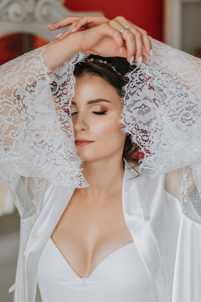 the bride in an open robe, open bust. Great hairstyle. lace robe, close-up portrait, looking into the camera - Фото, изображение