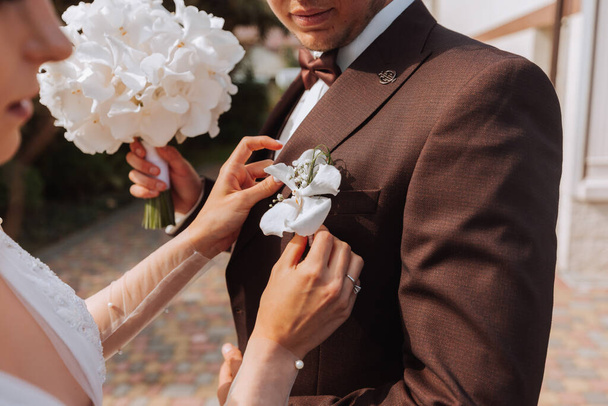 bride clings to the jacket of the groom's boutonniere of fresh flowers - Photo, image