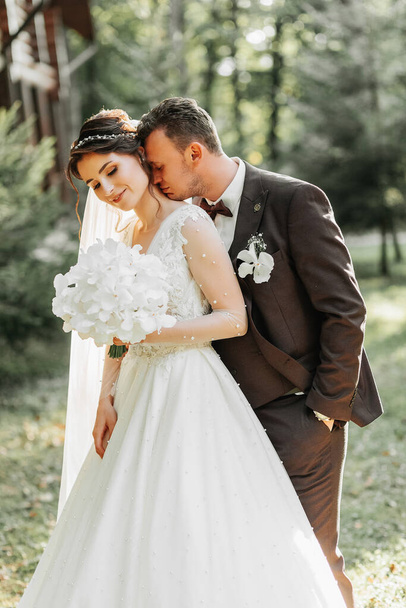 Amazing smiling wedding couple. A beautiful bride and a stylish groom. Kiss of the bride and groom - Photo, image