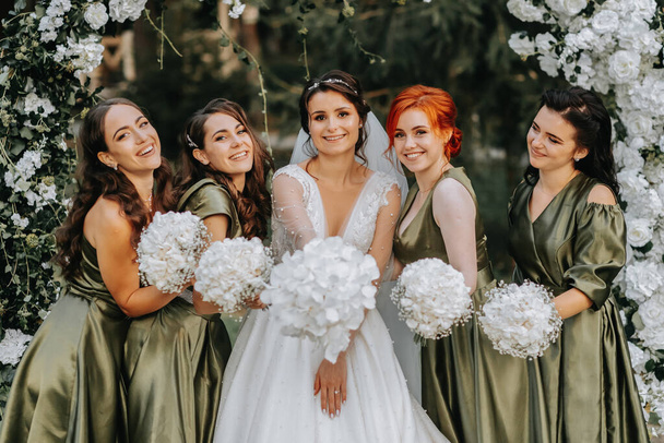 Bridesmaids smiling together with the bride. The bride and her fun friends celebrate the wedding after the ceremony in matching dresses. Bride and friends in nature - Fotoğraf, Görsel