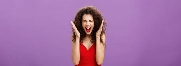 Woman going crazy screaming being tensed under pressure closing eyes. shaking hands and yelling distressed and upset losing control over emotions posing displeased and fed up over purple background. - 写真・画像