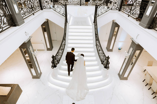 the bride and groom climb the stairs to celebrate the wedding, photo from above. - Zdjęcie, obraz