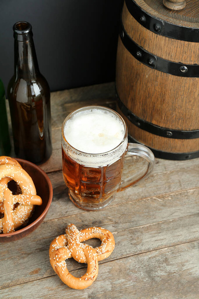 Hrnek studeného piva, preclíků, láhve a dřevěného sudu na stole. Oslava Oktoberfestu - Fotografie, Obrázek
