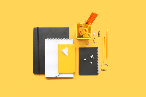 Notebooky, papírové letadlo a různé školní šablony na oranžovém pozadí - Fotografie, Obrázek