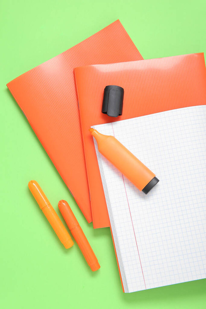 Оранжевые ноутбуки с маркерами на зеленом фоне - Фото, изображение