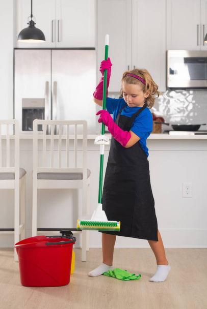 Portret dziecka sprzątanie, rozwój koncepcji, rozwój, relacje rodzinne. Koncepcja sprzątania i sprzątania domu. Dziecko używać odkurzacza i rękawice do czyszczenia. Home kuchnia tło - Zdjęcie, obraz
