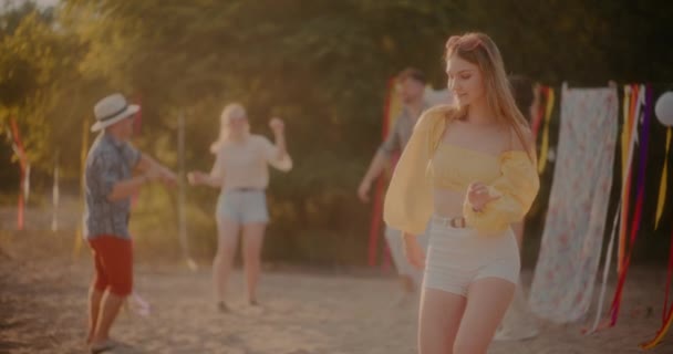 Krásná mladá žena drážkování proti přátelům tanec na pláži během letního víkendu - Záběry, video