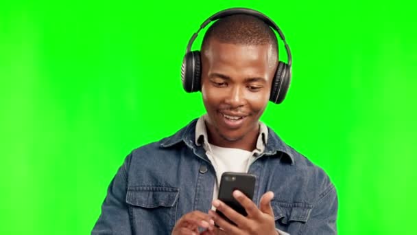 Telefon, zene fejhallgató és fekete férfi a zöld képernyőn a stúdióban elszigetelt háttérrel. Rádió, hallgatás és boldog afrikai ember táncol audio lejátszási lista, jazz podcast vagy streaming hip hop hang - Felvétel, videó