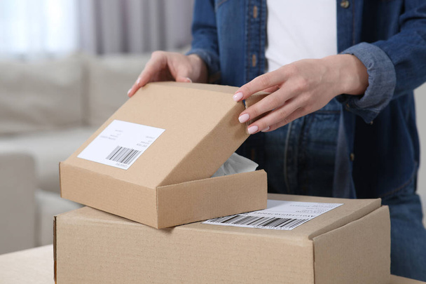 Woman unpacking parcel at home, closeup. Online store - Foto, afbeelding