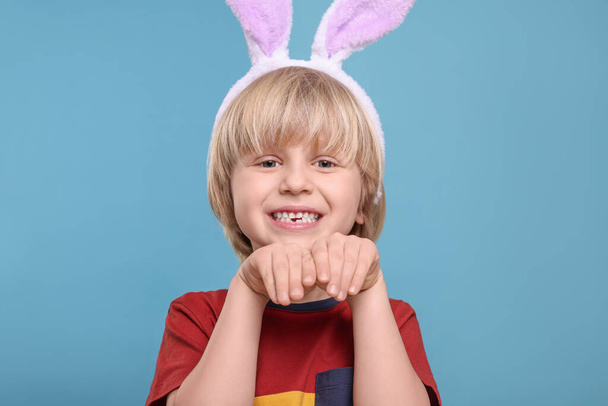 Happy boy wearing bunny ears headband on turquoise background. Easter celebration - Fotografie, Obrázek