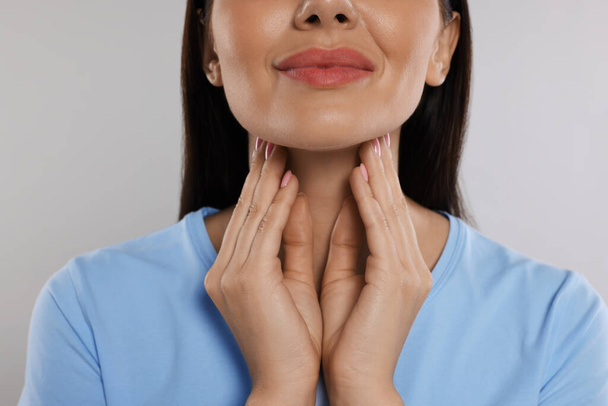 Endocrine system. Woman doing thyroid self examination on light grey background, closeup - Фото, зображення