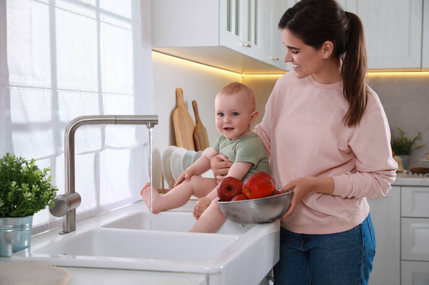 Mother and her cute little baby spending time together in kitchen - Foto, afbeelding