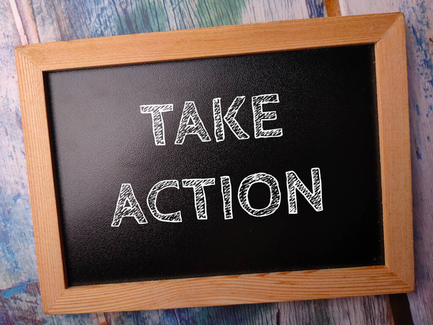 Houten zwart bord met het woord TAKE ACTION op een houten ondergrond - Foto, afbeelding
