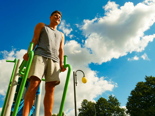 Young handsome man working out in outdoor gym. Sporty guy flexing his muscles on machine. Staying fit and healthy. - Fotoğraf, Görsel