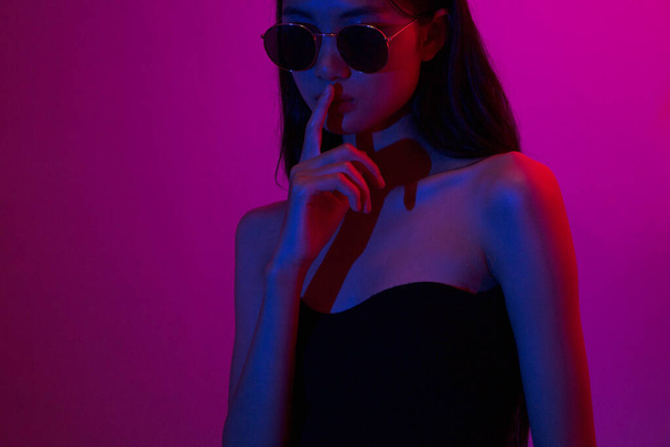Moda e concetto di bellezza, donna di moda con trucco glitter indossare occhiali da sole su sfondo neon. - Foto, immagini
